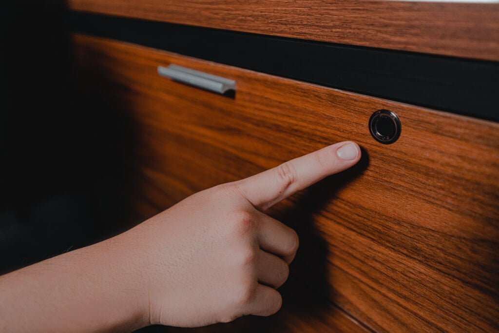 Finger pressing a finger print lock on the CEO desk's drawer, highlighting easy access and secure storage functionality.